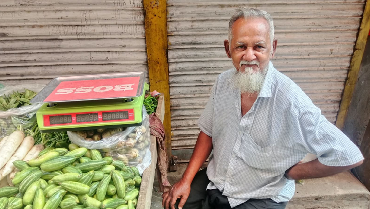শীতের সবজি নিয়ে হাসি মুখে বসে আছেন দোকানি